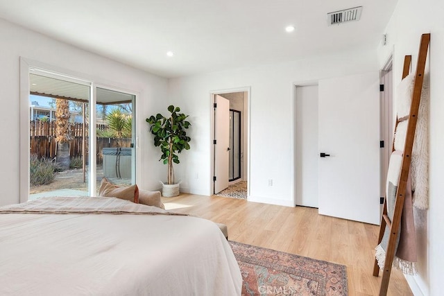 bedroom with access to outside, ensuite bath, and light hardwood / wood-style flooring