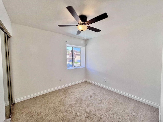 carpeted spare room featuring ceiling fan