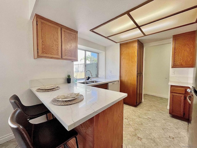 kitchen with white dishwasher, kitchen peninsula, sink, and a breakfast bar area