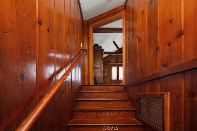 staircase with vaulted ceiling and wood walls