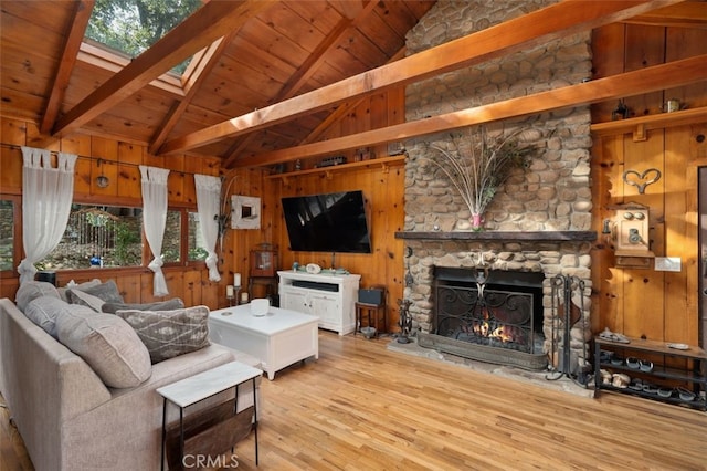 living room with a fireplace, a skylight, wooden walls, beamed ceiling, and hardwood / wood-style flooring