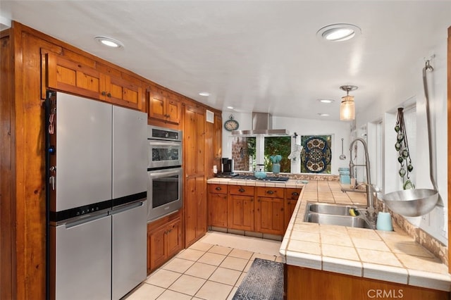 kitchen featuring sink, tile countertops, kitchen peninsula, and appliances with stainless steel finishes