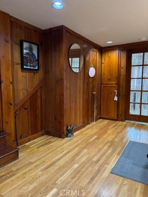 foyer with light wood-type flooring and wood walls