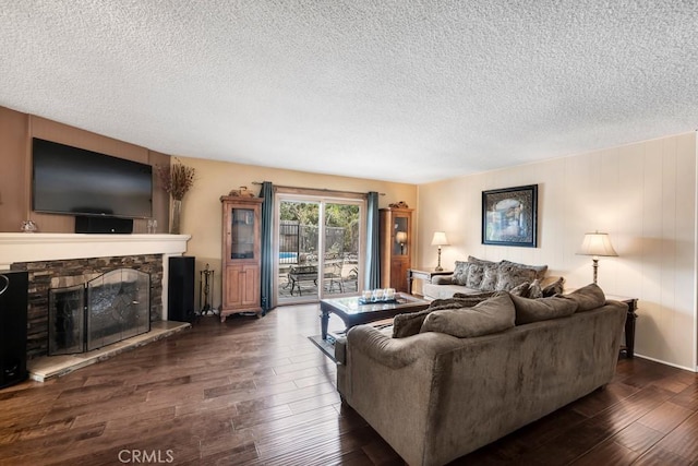 living room with a stone fireplace, dark hardwood / wood-style flooring, and a textured ceiling