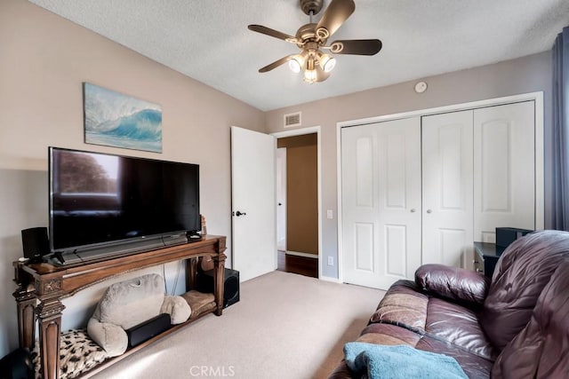 carpeted living room featuring a textured ceiling and ceiling fan