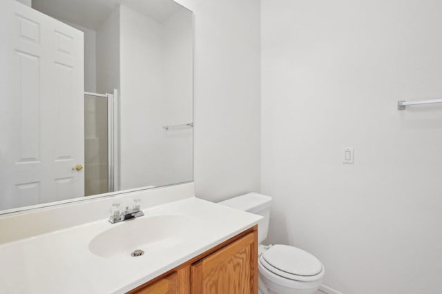 bathroom with walk in shower, vanity, and toilet