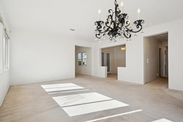 spare room featuring light carpet and a chandelier