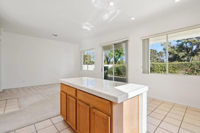 kitchen featuring tile counters, a center island, and light tile patterned flooring