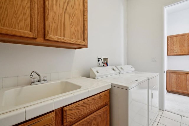 laundry room with cabinets, sink, washing machine and dryer, and light tile patterned floors