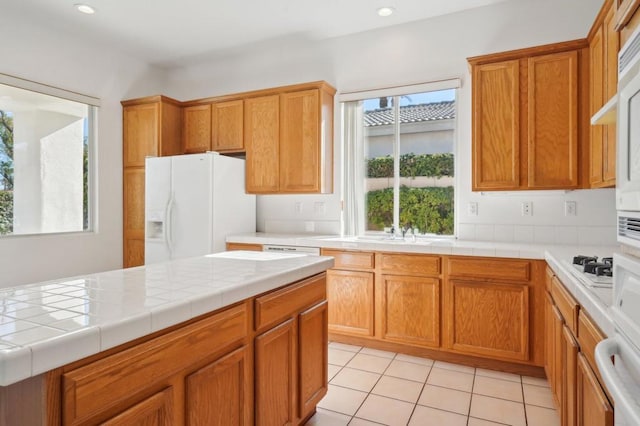 kitchen with tile countertops, white appliances, and light tile patterned floors