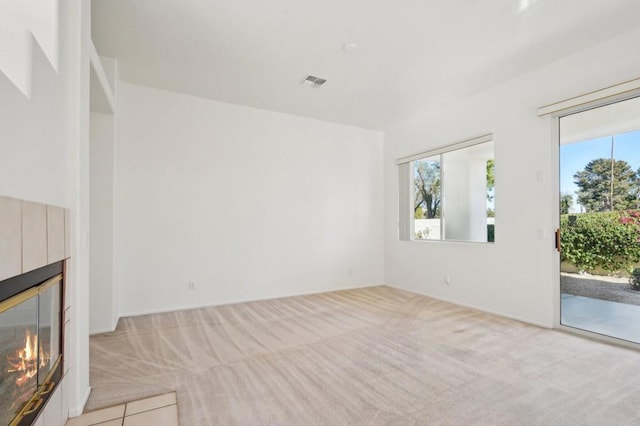 unfurnished living room featuring plenty of natural light and light carpet