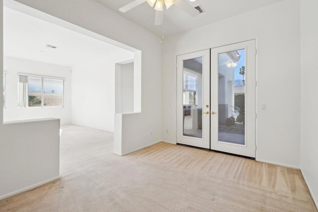 carpeted empty room featuring plenty of natural light, ceiling fan, and french doors