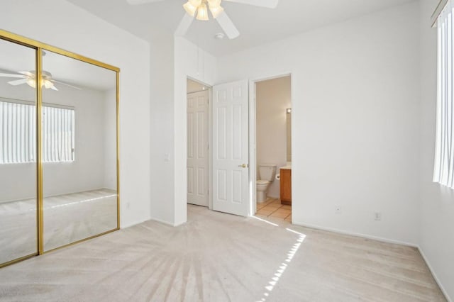 unfurnished bedroom featuring ensuite bathroom, light carpet, ceiling fan, and a closet