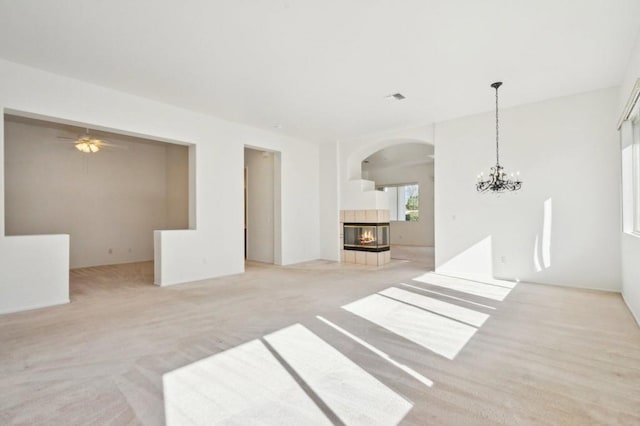 carpeted living room with a fireplace and ceiling fan with notable chandelier