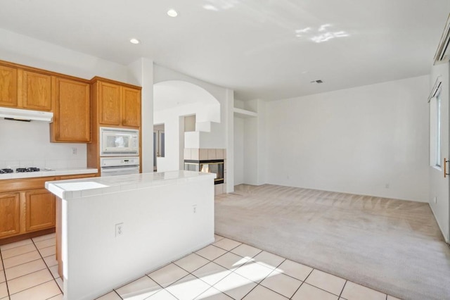 kitchen featuring light tile patterned floors, white appliances, tile counters, and a center island