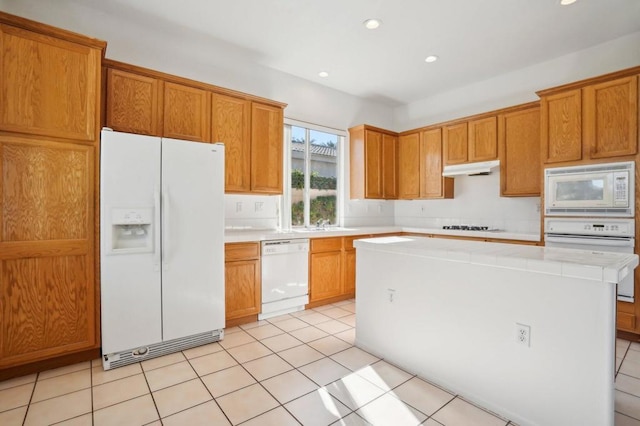 kitchen featuring sink, a center island, light tile patterned floors, and white appliances