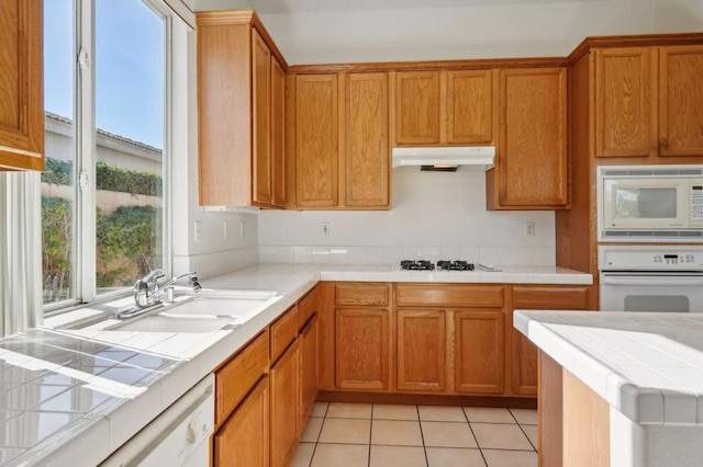 kitchen featuring sink, tile counters, white appliances, and light tile patterned floors