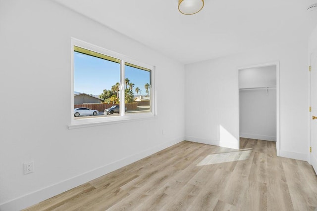 unfurnished bedroom featuring a spacious closet, light hardwood / wood-style floors, and a closet