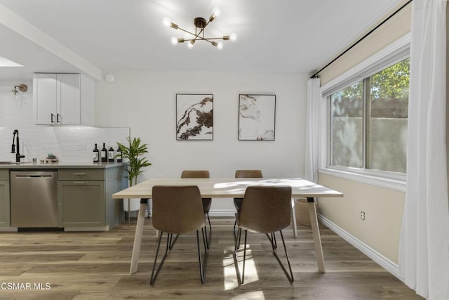 dining area with a chandelier, sink, and light wood-type flooring