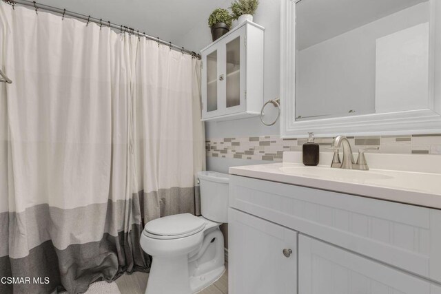 bathroom with a shower with curtain, vanity, toilet, and decorative backsplash