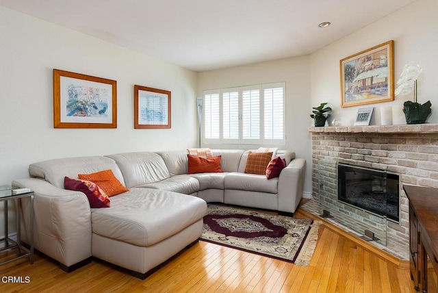 living room with a brick fireplace and hardwood / wood-style floors