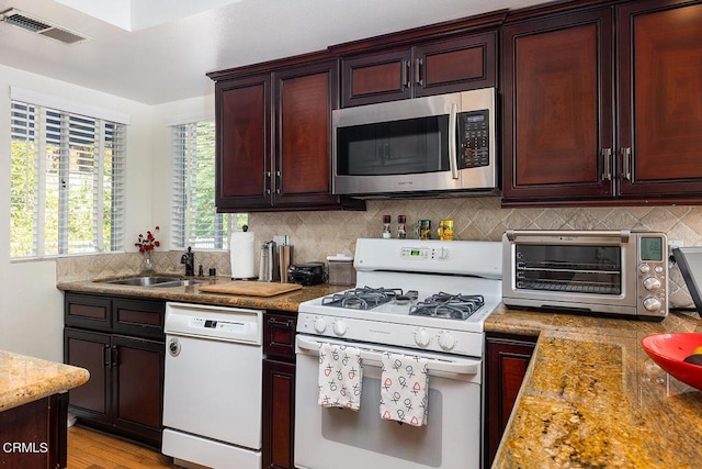 kitchen with sink, light wood-type flooring, white appliances, light stone countertops, and backsplash