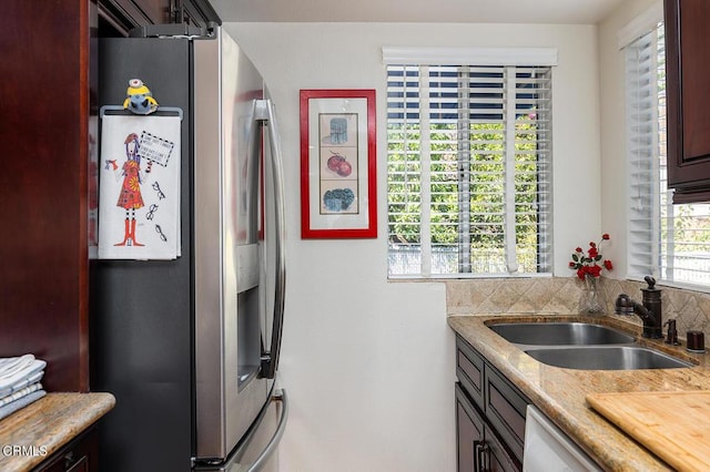 kitchen featuring light stone countertops, appliances with stainless steel finishes, sink, and dark brown cabinets