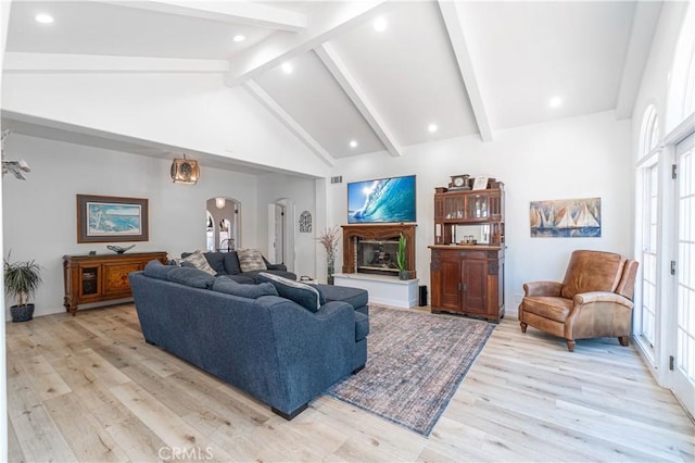 living room with a healthy amount of sunlight, high vaulted ceiling, light wood-type flooring, and beam ceiling