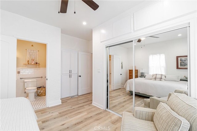 bedroom with ensuite bath, a closet, ceiling fan, and light wood-type flooring