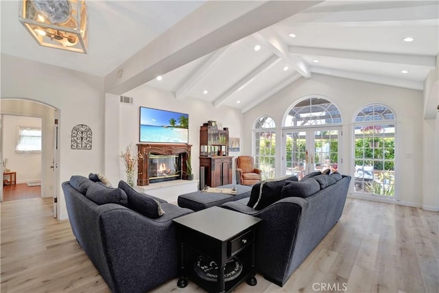 living room featuring vaulted ceiling with beams, french doors, and light wood-type flooring