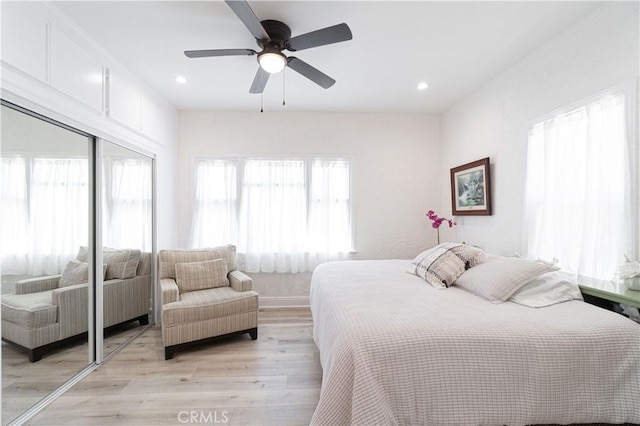 bedroom with light hardwood / wood-style flooring, a closet, and ceiling fan