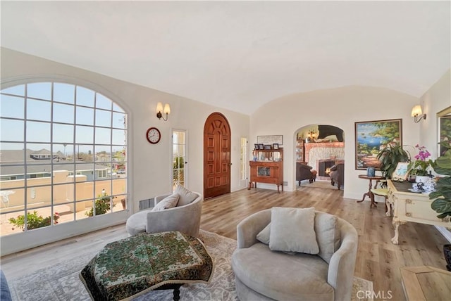 living room featuring brick ceiling, plenty of natural light, vaulted ceiling, a chandelier, and light wood-type flooring