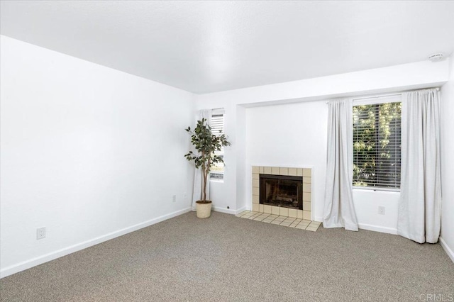 unfurnished living room featuring carpet floors, a fireplace, and baseboards