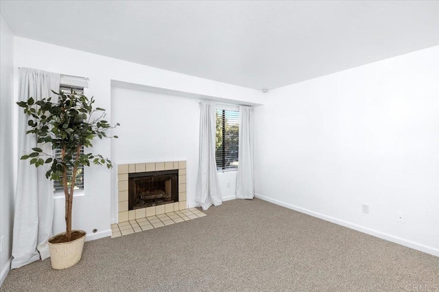 unfurnished living room featuring carpet floors, baseboards, and a tiled fireplace