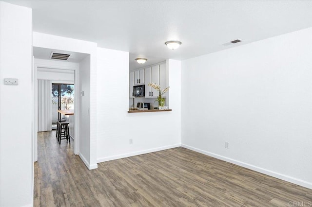 empty room featuring visible vents, baseboards, and wood finished floors