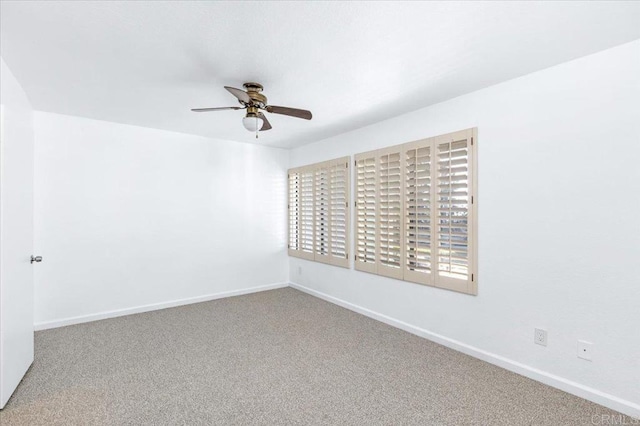 carpeted spare room featuring ceiling fan and baseboards