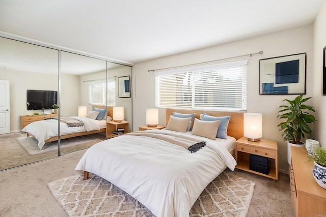 carpeted bedroom featuring multiple windows and a closet