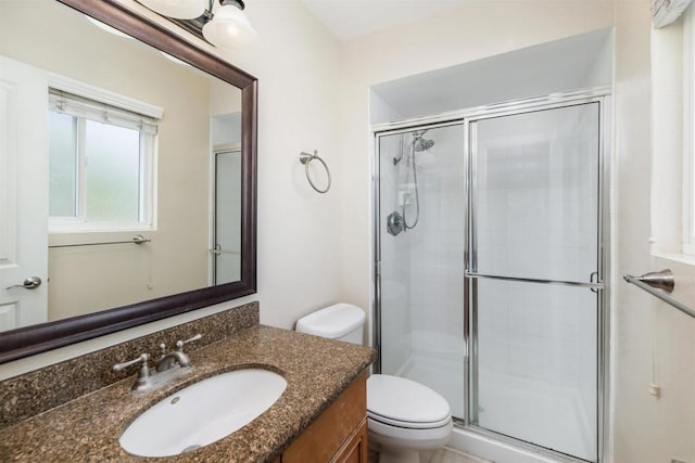 bathroom featuring vanity, a shower with door, and toilet