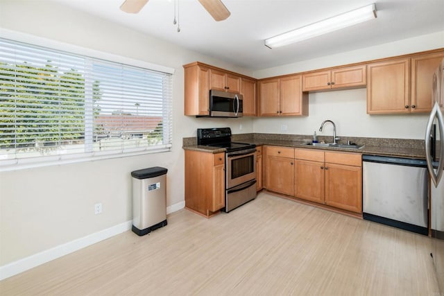 kitchen featuring stainless steel appliances, ceiling fan, sink, and light wood-type flooring