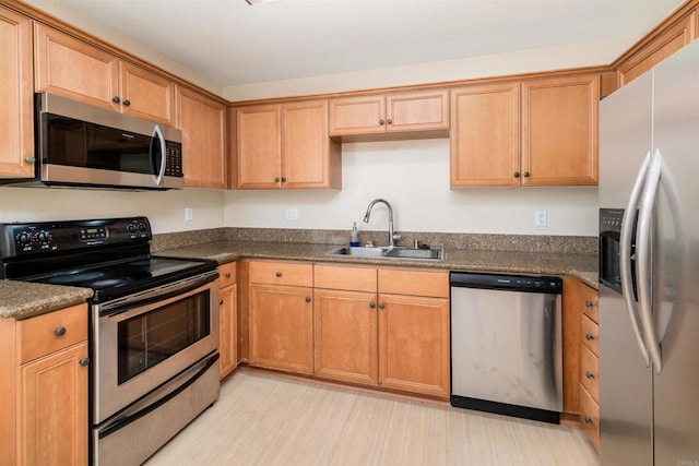 kitchen with appliances with stainless steel finishes, sink, and light wood-type flooring