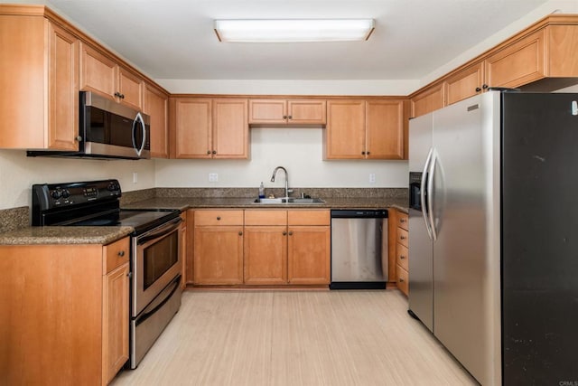 kitchen with appliances with stainless steel finishes, sink, and light hardwood / wood-style floors