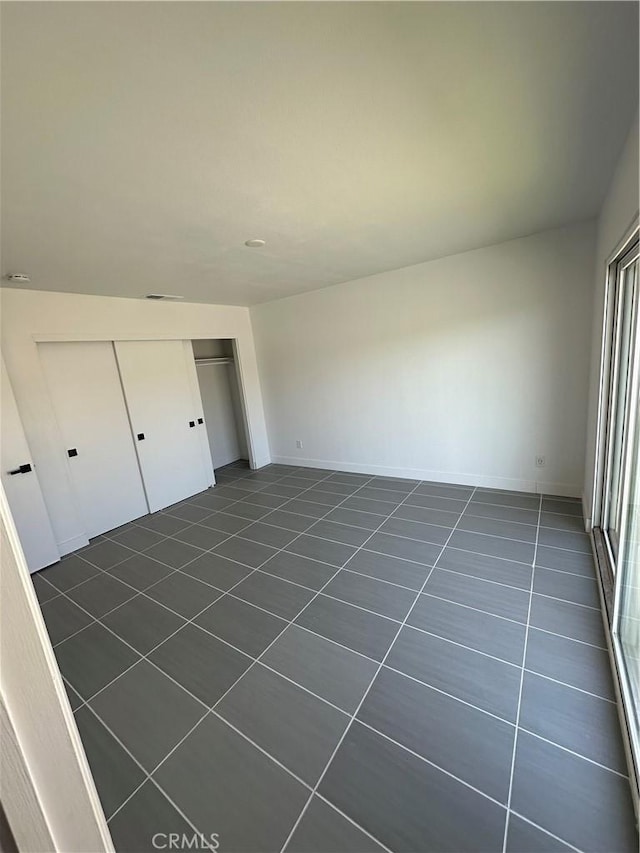 unfurnished bedroom featuring dark tile patterned flooring and a closet