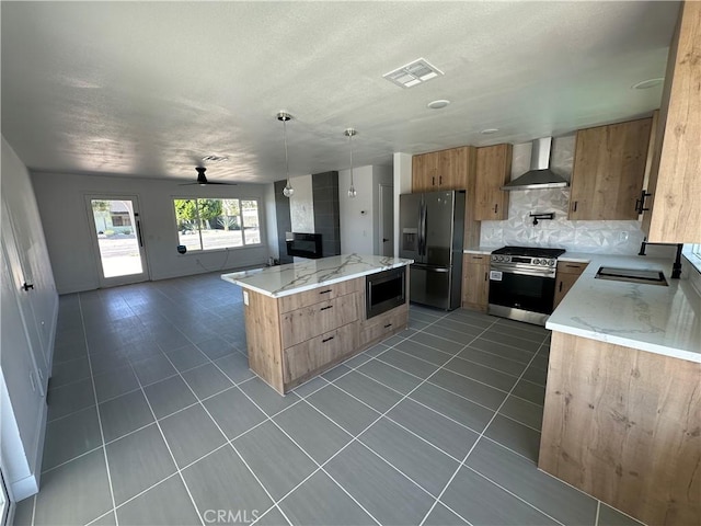 kitchen with sink, backsplash, stainless steel appliances, decorative light fixtures, and wall chimney exhaust hood