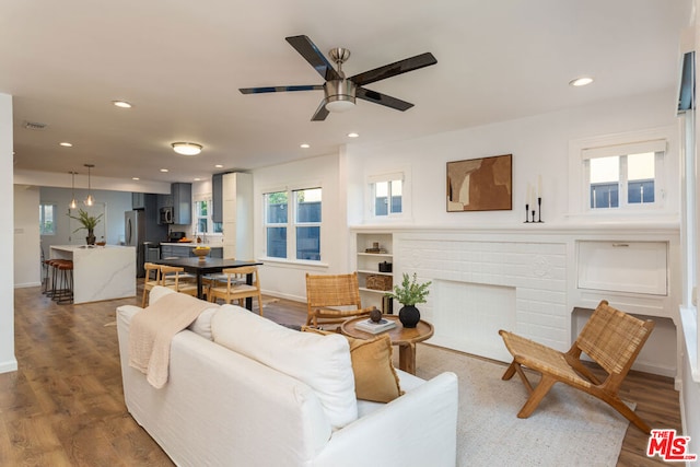 living room featuring hardwood / wood-style flooring, a brick fireplace, and ceiling fan