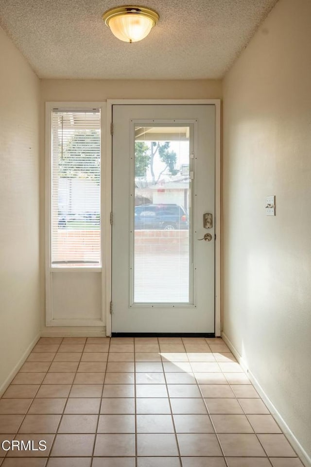 entryway featuring light tile patterned floors, a wealth of natural light, and a textured ceiling