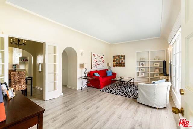 living room with built in features, a notable chandelier, light wood-type flooring, and french doors