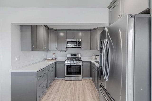 kitchen featuring appliances with stainless steel finishes, gray cabinets, and light wood-type flooring