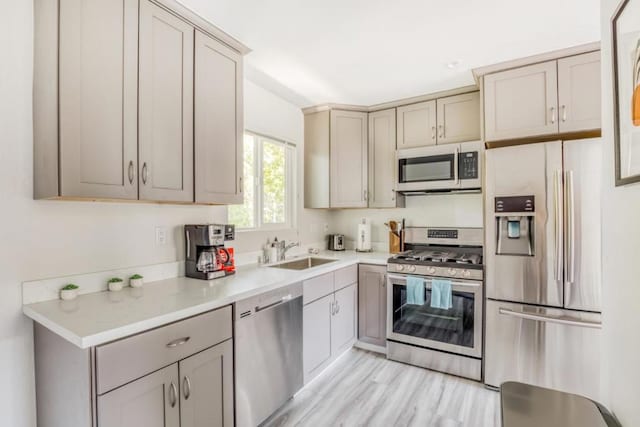 kitchen featuring appliances with stainless steel finishes, sink, and light hardwood / wood-style flooring