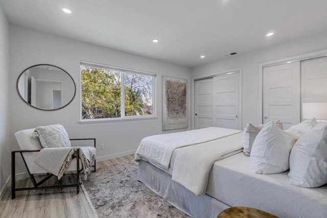 bedroom with light hardwood / wood-style floors and multiple closets