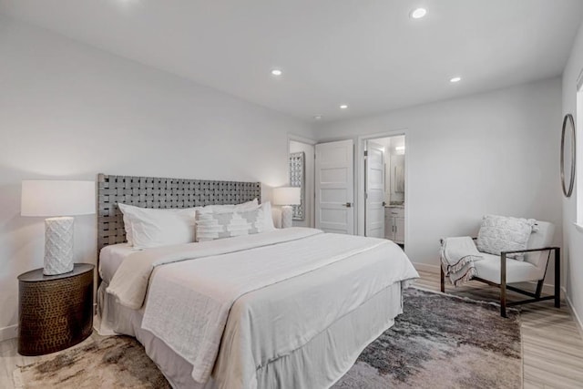 bedroom featuring connected bathroom and light hardwood / wood-style flooring